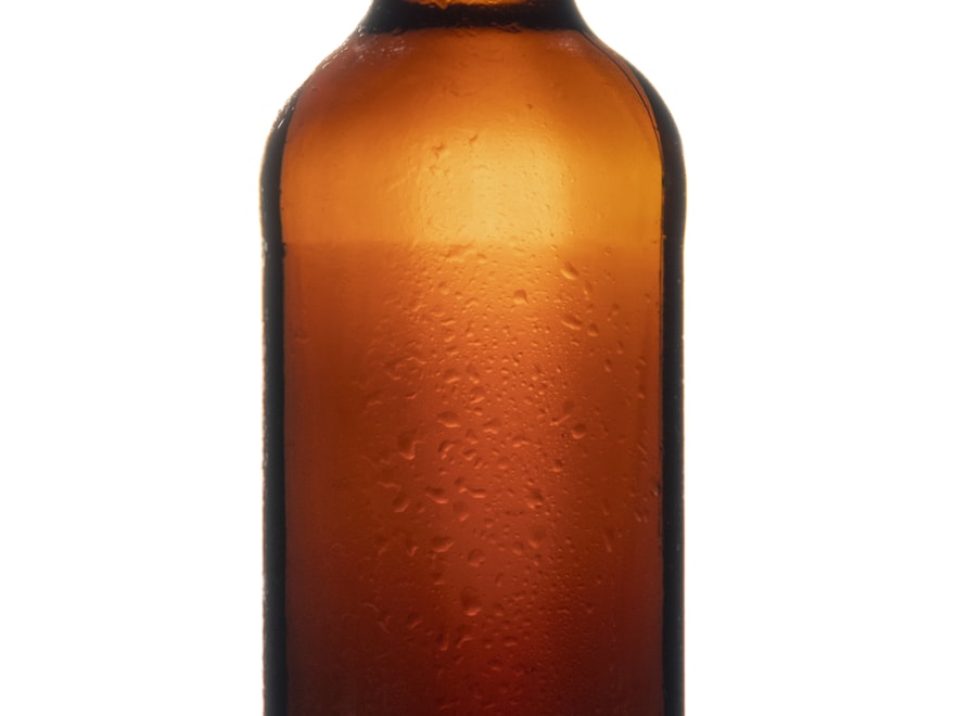 Chilled amber glass beer bottle on a pale backdrop
