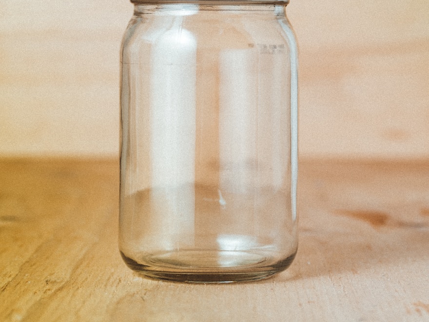 Empty clear glass preserve jar with a clamp lid on a wooden table