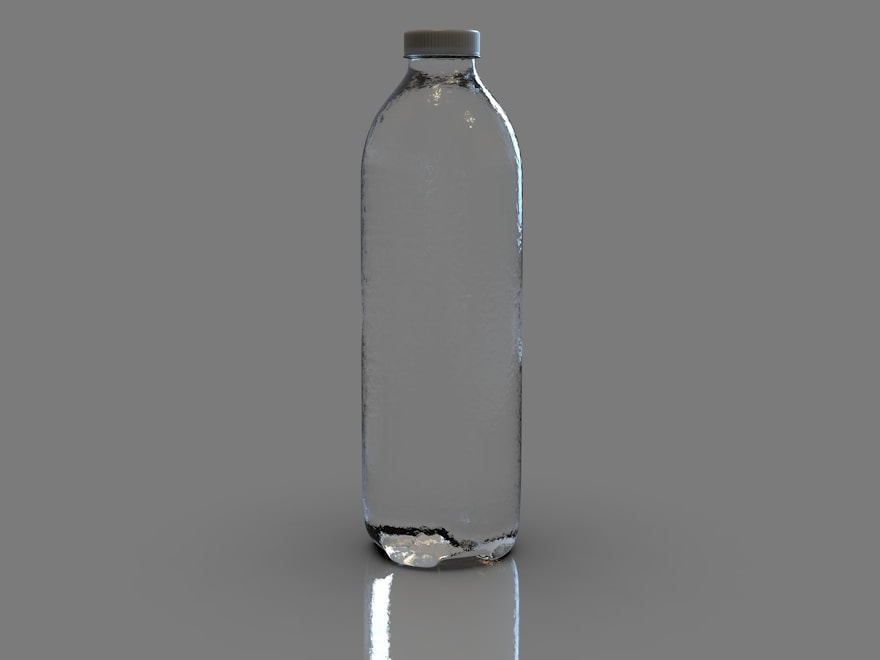 Clear glass juice bottle on a soft grey studio backdrop
