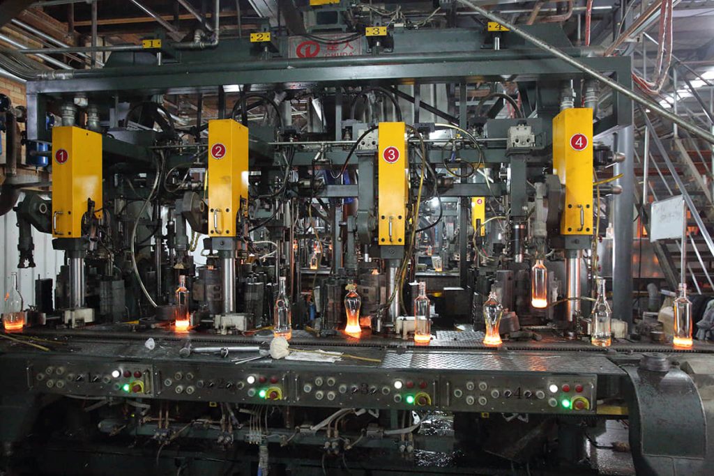 IS forming machine shaping red-hot glass bottles on the production line