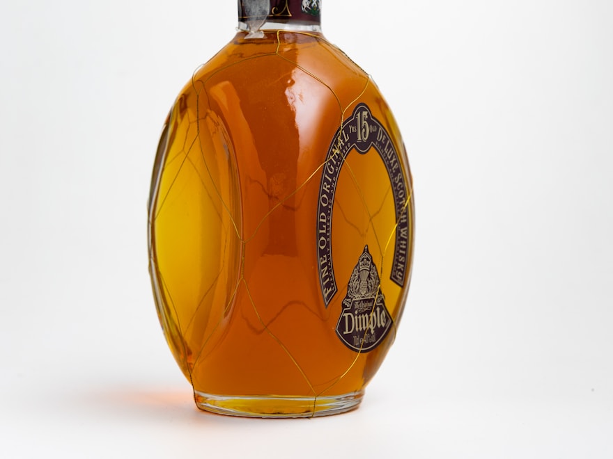 Amber glass honey jar, filled and capped, on a pale backdrop