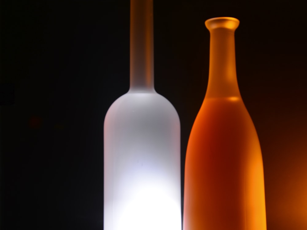 Color-coated frosted glass bottles in white and orange, backlit