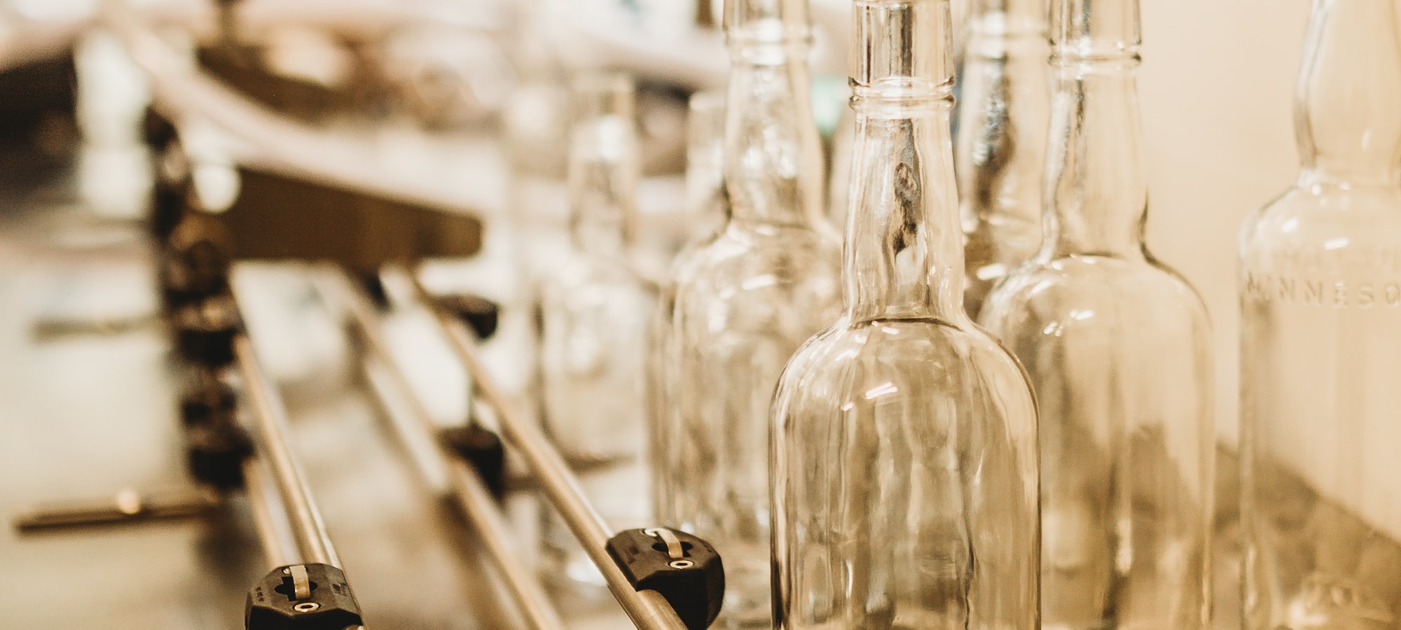 Empty clear glass bottles moving along a production conveyor line